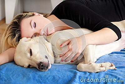 Woman with cute dogs at home. Handsome girl resting and sleeping with her dog in bed in bedroom. Owner and dog sleeping in sofa. Stock Photo