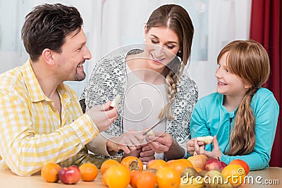 Woman cutting healthy fruits for her husband and daughter Stock Photo