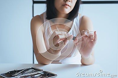 Woman cutting nails with nail clipper,Female using tweezers clipping hes fingernails Stock Photo