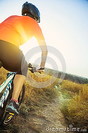 Woman cyclist with the glare from the setting sun. Stock Photo