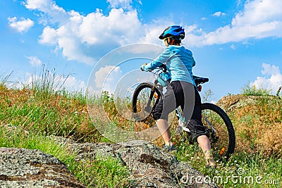 Woman cyclist pushing her bike up a steep slope Stock Photo