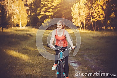 Woman cyclist rides in the forest on a mountain bike. Stock Photo