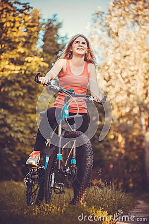 Woman cyclist rides in the forest on a mountain bike. Stock Photo