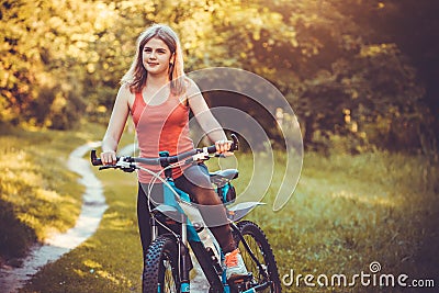 Woman cyclist rides in the forest on a mountain bike. Stock Photo