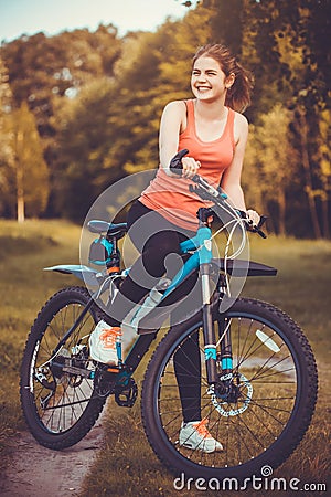 Woman cyclist rides in the forest on a mountain bike. Stock Photo