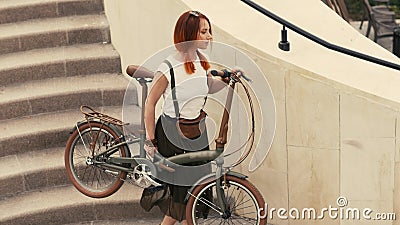 Woman cyclist walking down stairs and holding bicycle in arms. Woman bike city Stock Photo