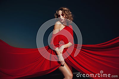 Woman dancing in silk dress, artistic red blowing gown waving and flittering fabric Stock Photo