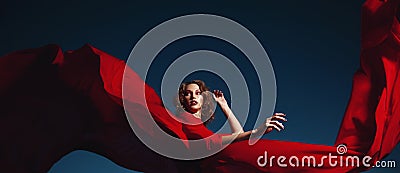 Woman dancing in silk dress, artistic red blowing gown waving and flittering fabric Stock Photo