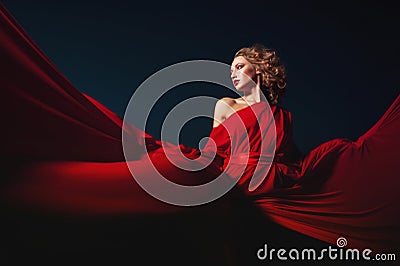 Woman dancing in silk dress, artistic red blowing gown waving and flittering fabric Stock Photo