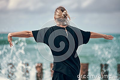 Woman dancing to music on sea coast, rear view, dancers at outdoor art performance music festival Stock Photo