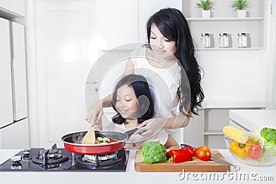 Woman and daughter cooking vegetable Stock Photo