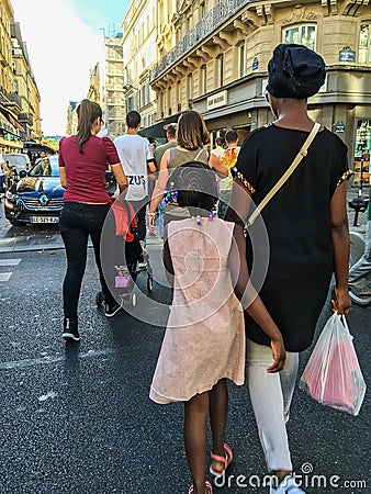 Woman and daughter stroll down Paris street among diverse crowd Editorial Stock Photo