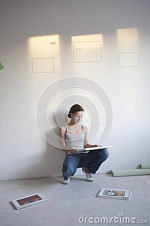 Woman Decides On Pictures To Mount In New Apartment Stock Photo