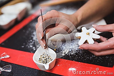 Woman decorates christmas gingerbread cookies with icing sugar glaze snowflake. Christmas gift, homemade gingerbread Stock Photo