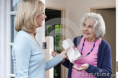 Woman Delivering Newspaper To Elderly Neighbour Stock Photo