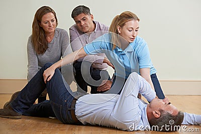 Woman Demonstrating Recovery Position In First Aid Training Class Stock Photo