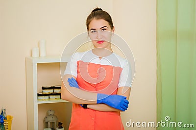 Woman, a depilation master in a red and white robe and blue gloves, a beauty salon worker Stock Photo