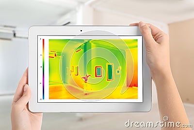 Woman detecting heat loss in room using thermal viewer. Energy efficiency Stock Photo