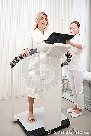 Woman diagnostician performs bioimpedancemetry diagnostic procedure in clinic Stock Photo