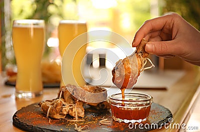 Woman dipping tasty BBQ wing into sauce at table Stock Photo