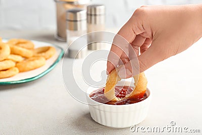 Woman dipping tasty onion ring into bowl Stock Photo