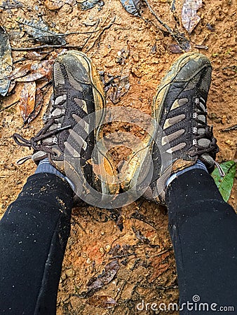 Woman with dirty brown hiking shoes resting on wet muddy area Stock Photo