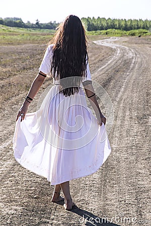 Woman on the dirty road from behind Stock Photo