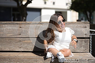 Woman with disability, reduced mobility and small stature sitting on a wooden bench, happy and relaxed sunbathing. Concept Stock Photo