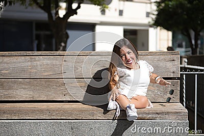 Woman with disability, reduced mobility and small stature sitting on a wooden bench, happy and relaxed sunbathing. Concept Stock Photo