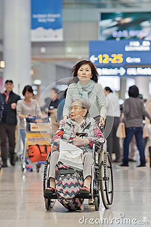 Woman with disabled mother in a wheelchair at Icheon Airport, Seoul, South Korea Editorial Stock Photo