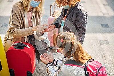 Woman is disinfecting kids hands with sanitizer Stock Photo