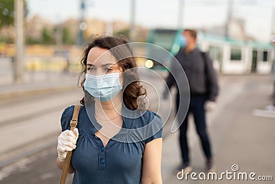 Woman in disposable mask at tram stop Stock Photo