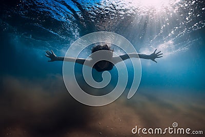 Woman dive without surfboard under wave. Underwater duck dive under wave and sandy bottom Stock Photo