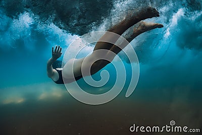 Woman dive without surfboard under wave. Underwater duck dive under wave and sandy bottom Stock Photo