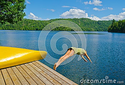 Woman diving off the dock into lake on a hot summer day Stock Photo