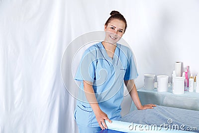 Woman doctor beautician closes the massage table with a disposable shee Stock Photo