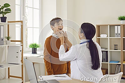 Woman doctor endocrinologist or otolaryngologist is examining her child patient Stock Photo