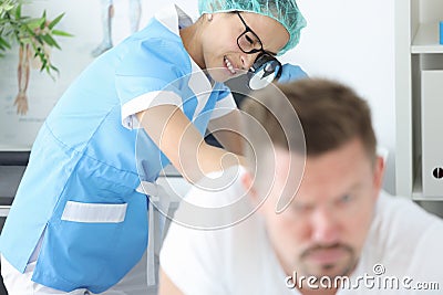 Woman doctor with glasses examining rash on skin of buttocks of young man in clinic Stock Photo