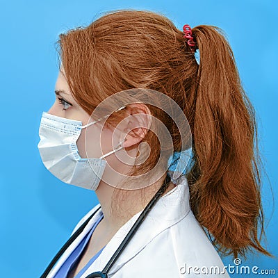 Woman doctor in medical mask on blue background, profile portrait. Coronavirus epidemic, flu virus quarantine concept Stock Photo