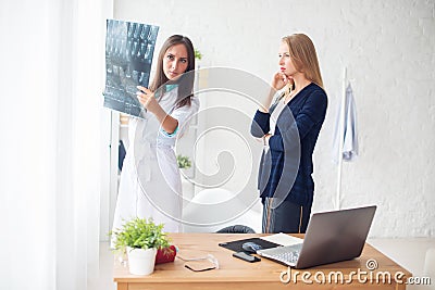 Woman doctor and patient in hospital looking at x-ray film healthcare, roentgen, people medicine concept. Stock Photo