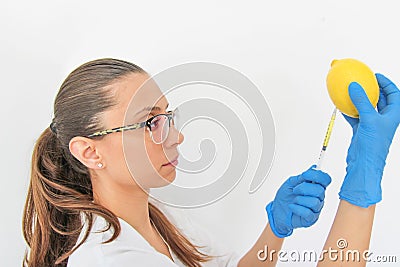 A woman doctor with a syringe in the laboratory extracts vitamin C from a lemon Stock Photo