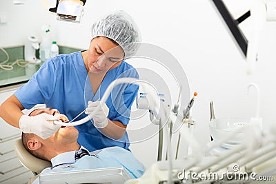 Woman doctor treats patient teeth using boron machine in clinic Stock Photo