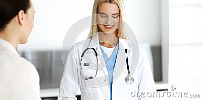 Woman-doctor at work in hospital is happy to communicate with female patient. Blonde physician checks medical history Stock Photo