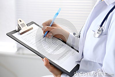 Woman doctor at work at hospital. Young female physician write prescription or filling up medical form while sitting in Stock Photo