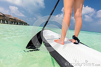 Woman does stand up paddle boarding on the ocean in Maldives Stock Photo