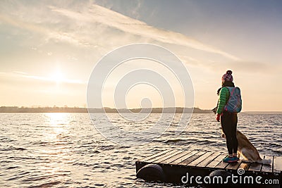 Woman with dog enjoy sunrise at lake, backpacker Stock Photo