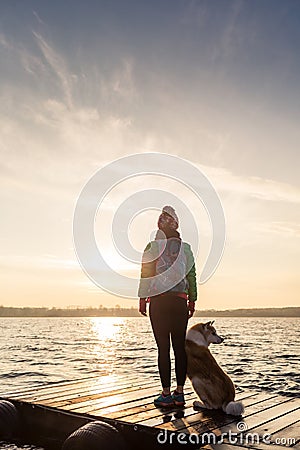 Woman with dog enjoy sunrise at lake, backpacker silhouette Stock Photo