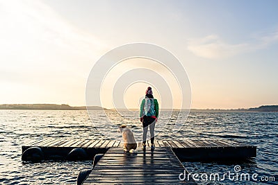 Woman with dog enjoy sunrise at lake, backpacker Stock Photo