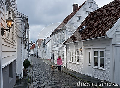 Woman and dog in narrow cobblestone street in Stavanger Norway Editorial Stock Photo