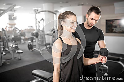 Woman doing bicep curls in gym with her personal trainer Stock Photo